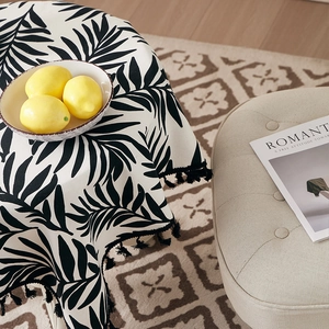 Detail of tropical palm leaf tablecloth featuring black tassel fringe on cotton linen fabric