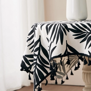 Close-up of tropical palm leaf pattern tablecloth with decorative black fringe tassels