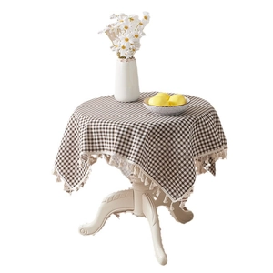 Brown checkered cotton linen tablecloth with beige tassels on round table