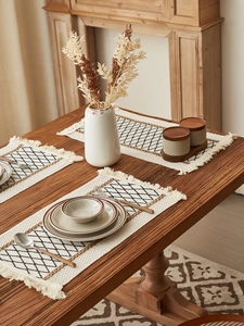 Macro view of woven placemat with geometric diamond pattern and decorative fringe edges