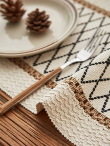Close-up of geometric woven cotton linen table runner with tassels on a dark wood table