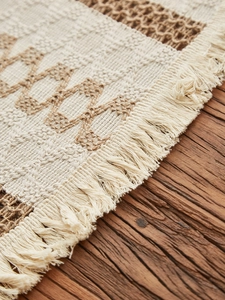 Close-up of bohemian woven cotton linen placemat with geometric pattern and fringe trim