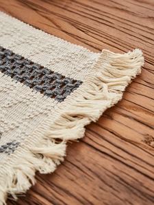 Close-up of woven cotton table runner featuring bohemian geometric patterns and fringe