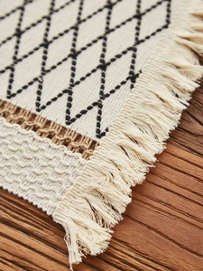 Macro shot of boho cotton woven table runner with black diamond patterns and thick tassels