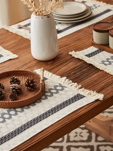 Close-up of bohemian woven table runner with geometric patterns and handmade tassels