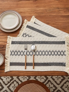Detail of bohemian cotton table runner featuring grey geometric patterns and fringe