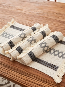 Detail of bohemian cotton table runner with woven geometric patterns and long fringes