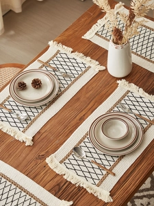 Close-up of bohemian woven cotton placemat with black diamond pattern and fringe