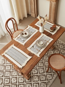 Close-up of woven cotton table runners with black diamond patterns and white tassels