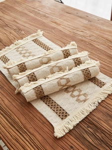 Macro detail of bohemian woven cotton linen placemat with fringe and geometric pattern