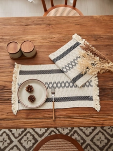 Close-up of Bohemian woven table runner with tassels and geometric patterns on wood