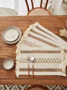 Detailed view of woven cotton linen placemats with brown stripes and fringe edges
