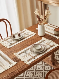 Detail of woven placemats and table runner with brown geometric patterns and fringe tassels