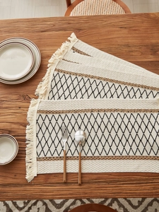Detail of woven table mat with geometric diamond patterns and delicate tassels