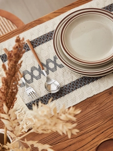 Detail of bohemian cotton woven table runner with grey diamond pattern and tassels