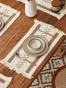 Detail of bohemian hand-woven table runner with geometric patterns and fringe tassels