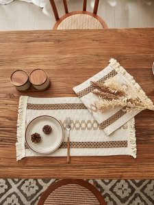 Macro view of woven placemat showing boho tassels and geometric cotton linen texture