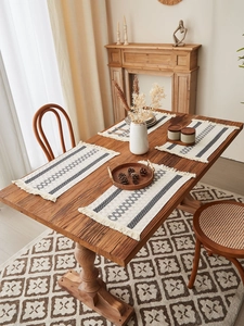 Detailed view of bohemian woven cotton linen placemats with tassels on a wooden table