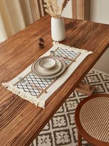 Close-up of woven cotton table runner featuring black diamond patterns and fringe edges