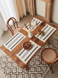 Close-up of bohemian cotton table runner with gray geometric patterns and tassel edges