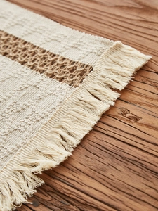 Macro view of woven table runner with boho tassels and hollow dark brown stripes