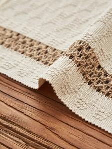 Macro detail of bohemian cotton woven table runner with tassels on a vintage wood surface