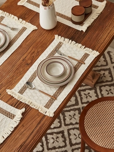 Detailed close-up of woven cotton table runner with boho tassels on a wooden surface
