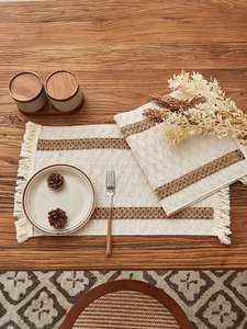 Detailed view of woven cotton linen table runner with tassel fringe on a wooden surface