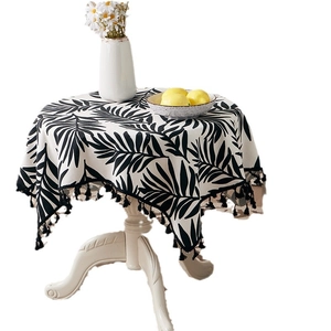 Round tropical leaf pattern cotton linen tablecloth with black tassels on white table