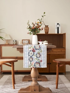 Close-up of vintage floral table runner on a wooden table with linen fabric texture