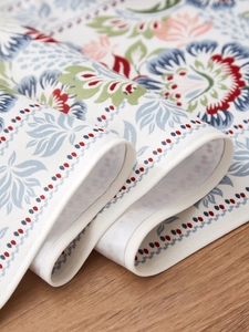 Close-up of bohemian floral fabric texture with fine white edge stitching on wooden table