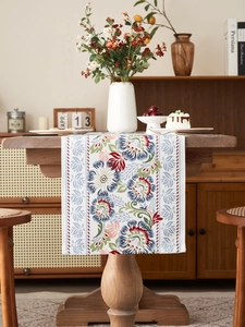 Close-up of vintage floral table runner with red and blue blooms on a wooden dining table