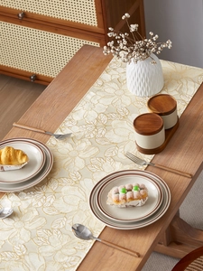 Detailed close-up of champagne gold floral embroidery on a premium cream table runner