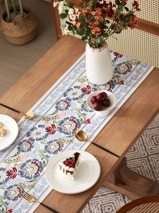 Detailed top view of a classic floral table runner on a rustic wooden dining table