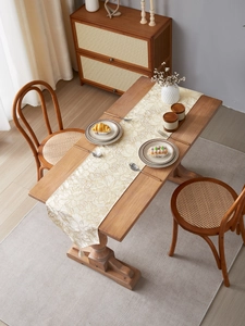Detailed view of cream table runner with gold floral embroidery and white tassels