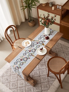 Detail of vintage floral table runner with red and teal patterns on solid wood table