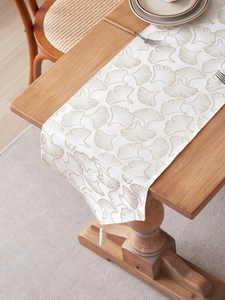 Macro detail of table runner with ginkgo leaf pattern and decorative white tassels