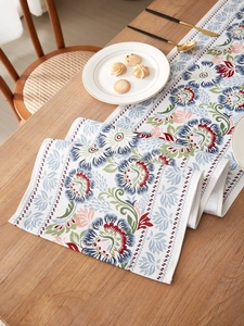 Detail of vintage floral table runner with blue and red patterns on white cotton linen