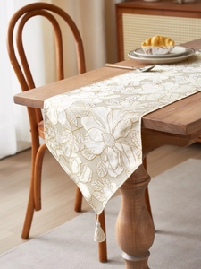 Detail of floral embroidery and cream tassels on a premium jacquard table runner