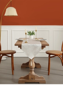 Detailed view of white leaf patterned table runner with elegant fringe tassels on wood