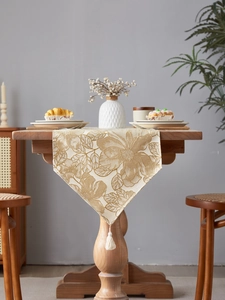 Detailed view of beige gold floral jacquard table runner with decorative white tassels