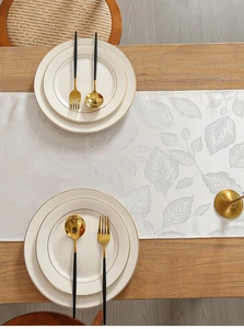 Vue détaillée du chemin de table jacquard blanc nacré avec motifs de feuilles sur bois