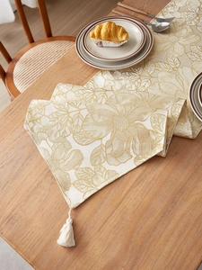 Detail of floral embroidery on cream table runner with elegant fringe and tassels