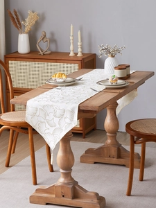 Close-up of beige table runner featuring golden ginkgo leaf jacquard and elegant tassels
