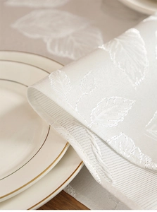Gros plan du motif jacquard de feuilles élégant sur un chemin de table blanc ivoire