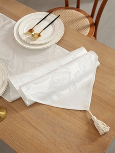 Détail du chemin de table blanc avec jacquard à motif de feuilles et glands élégants