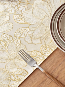 Detailed close-up of premium beige table runner with intricate gold floral embroidery