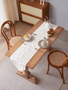 Detail of cream table runner with golden ginkgo leaf patterns and elegant tassels