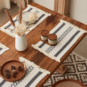 Bohemian woven table runner with grey geometric patterns and fringe on dark wood table