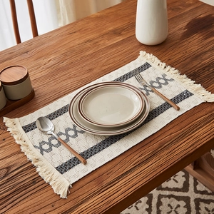 Retro cream woven table runner with gray geometric patterns and fringed tassels on wood